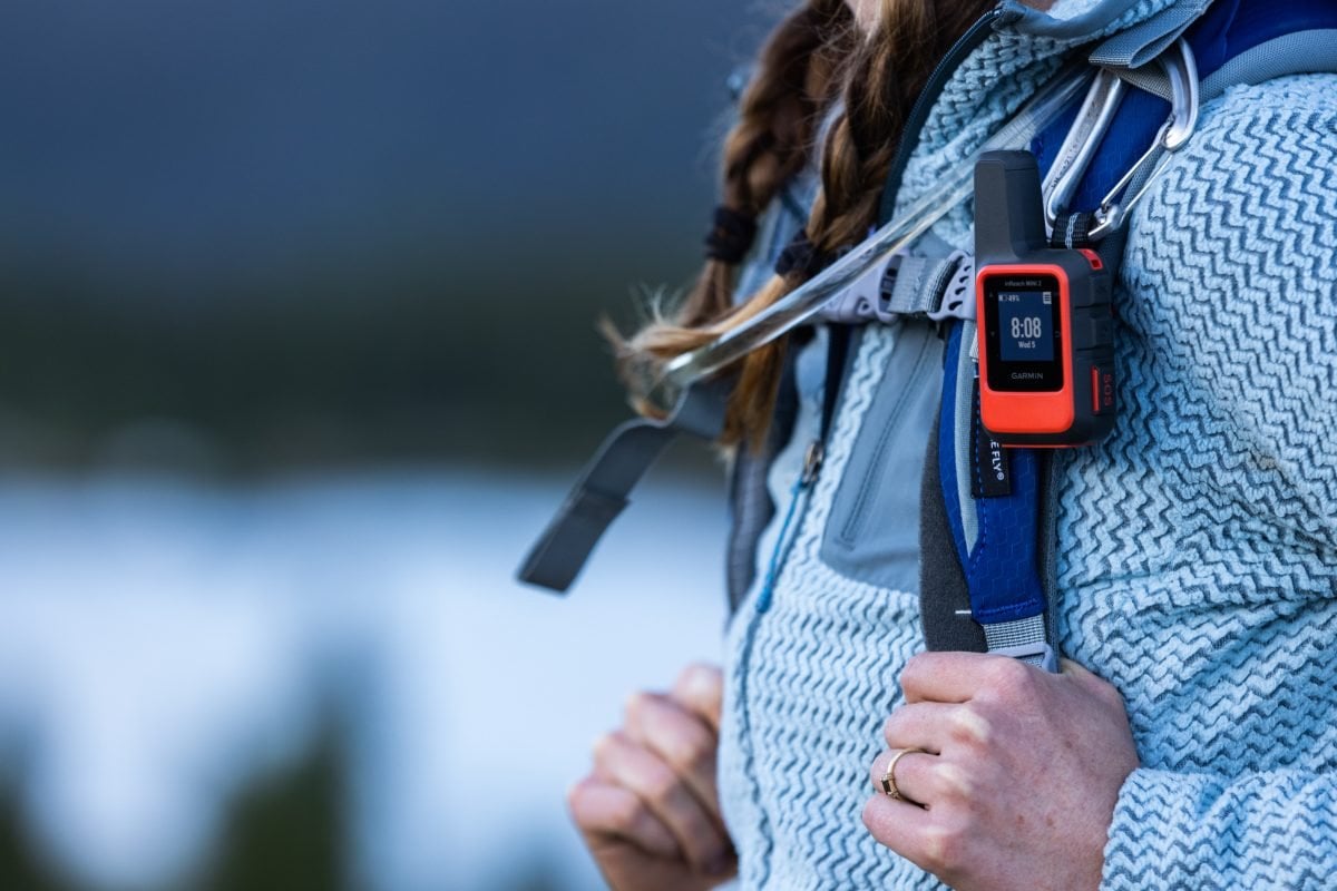A close up of a Garmin inReach mini attached to the strap of an Osprey backpacking pack