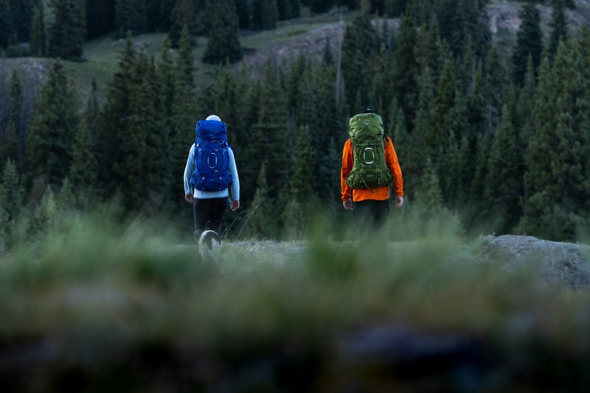 Two backpackers walking along trail in the backcountry in full backpacking gear