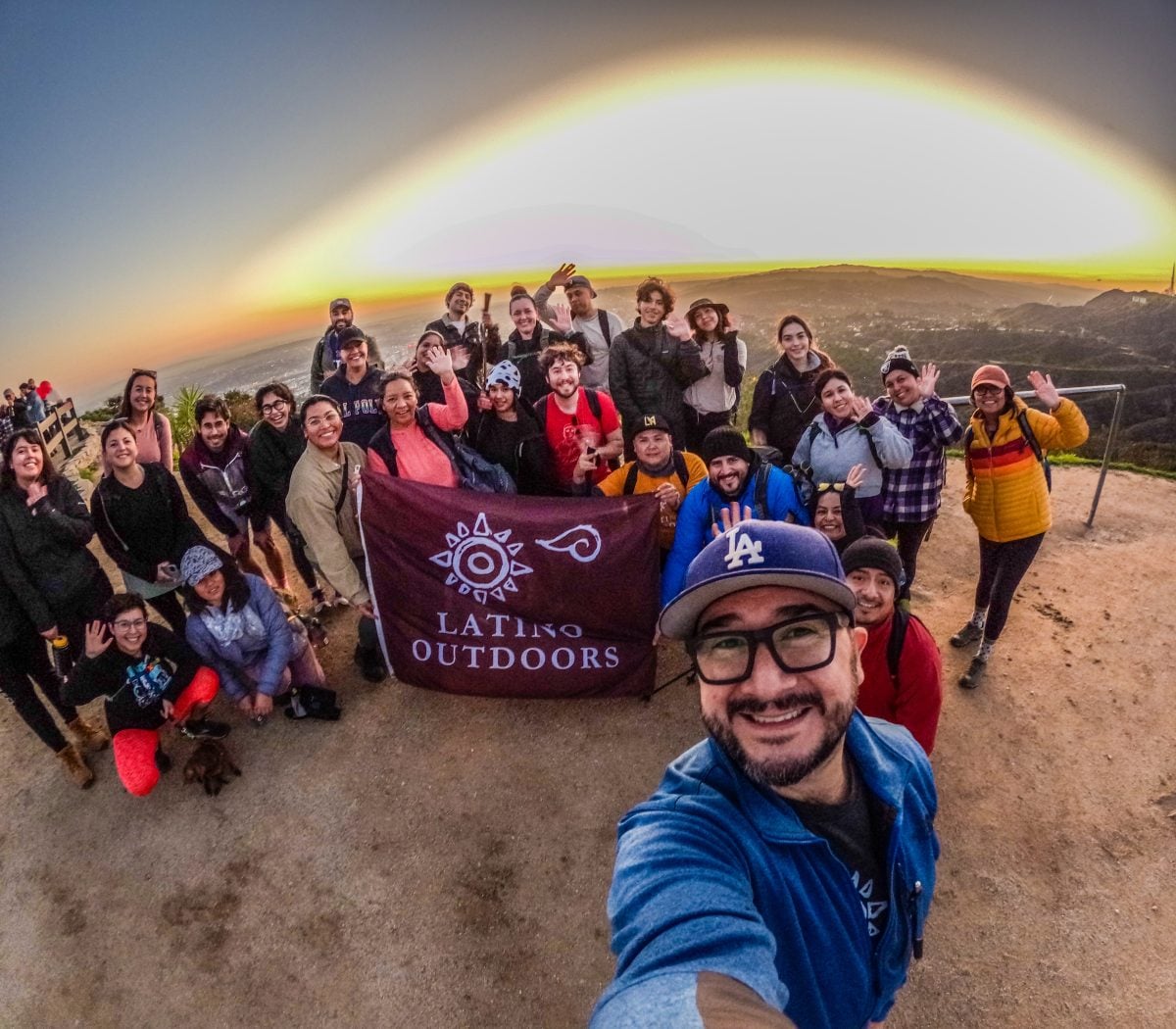 A group of people standing atop a trail holding a Latino Outdoors flag