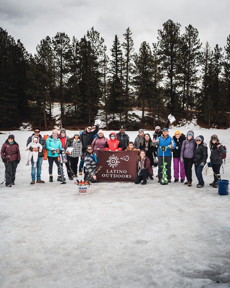A group of people outside in the snow, gathered around a Latino Outdoors flag
