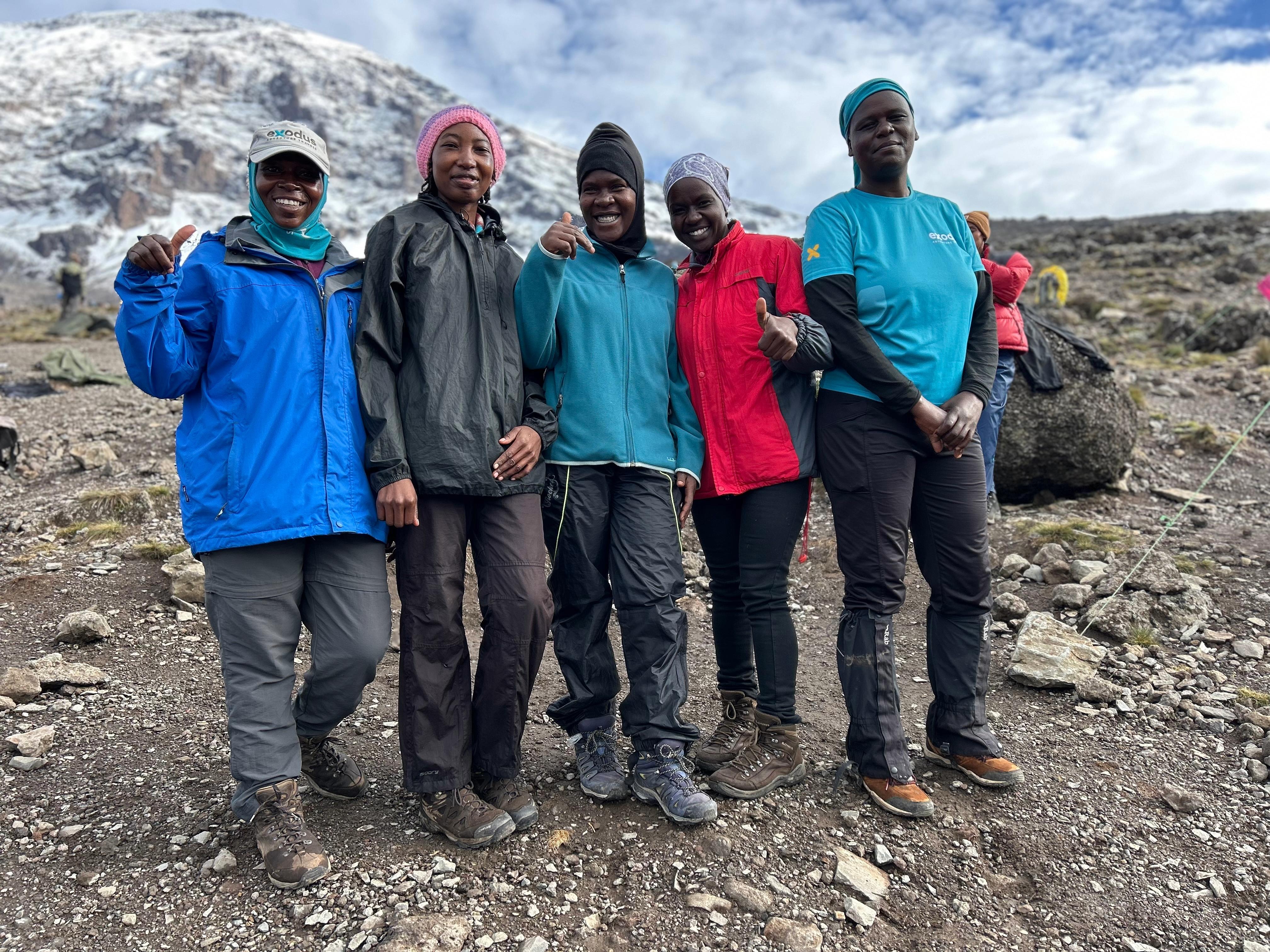 Five female porters pose in front of Kilimanjaro