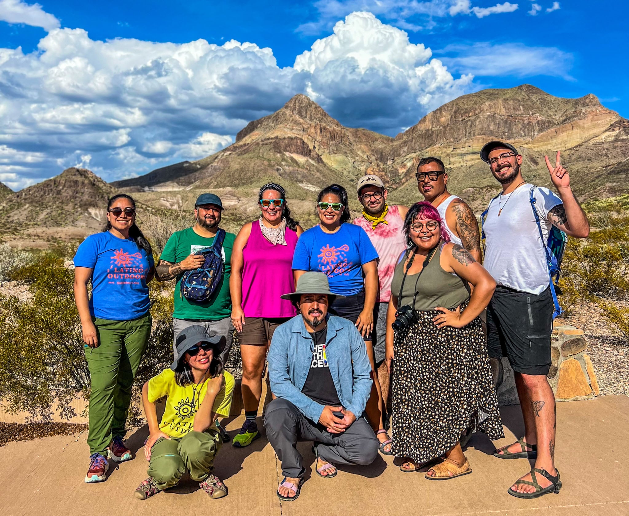 A group of adventurers pose in front of desert mountains.