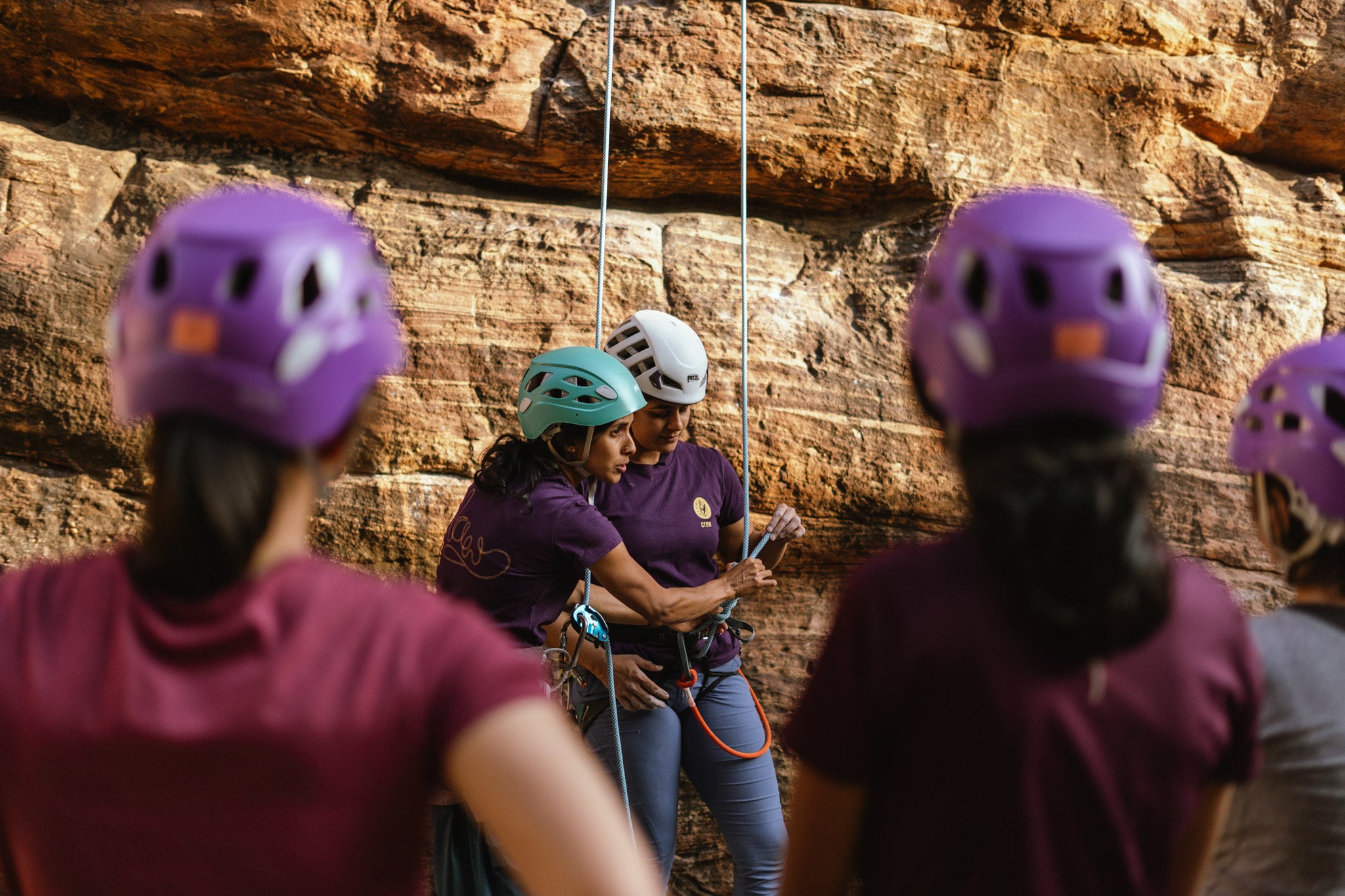 A woman instructs a group of female climbers.
