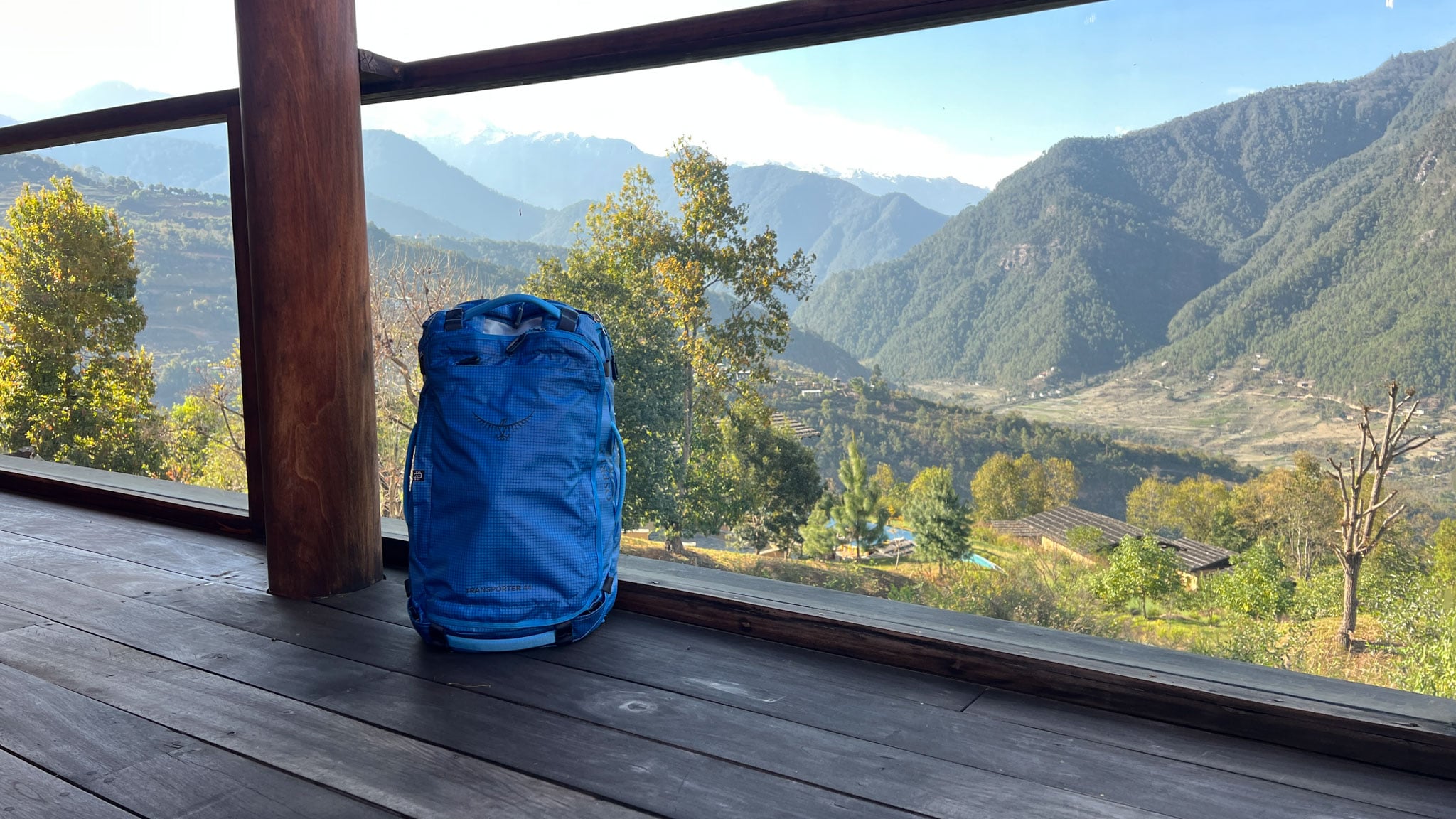 A duffel bag sits on a porch overlooking a view of mountains.
