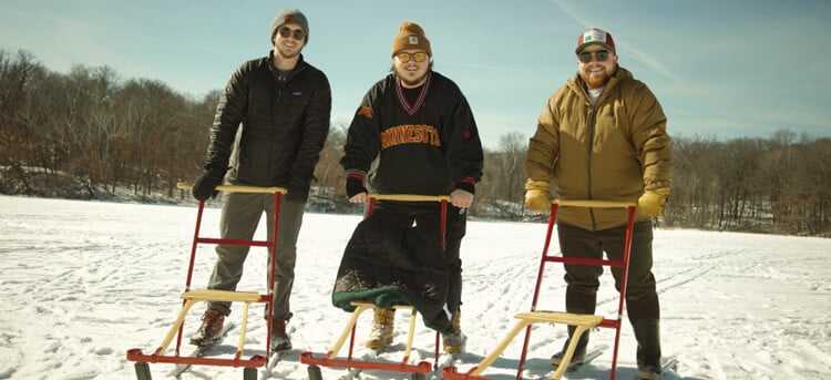 Three TVOP participants stand bundled up on a frozen lake with their kicksleds.