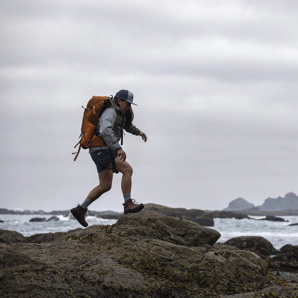 Person backpacking across a rocky shore.