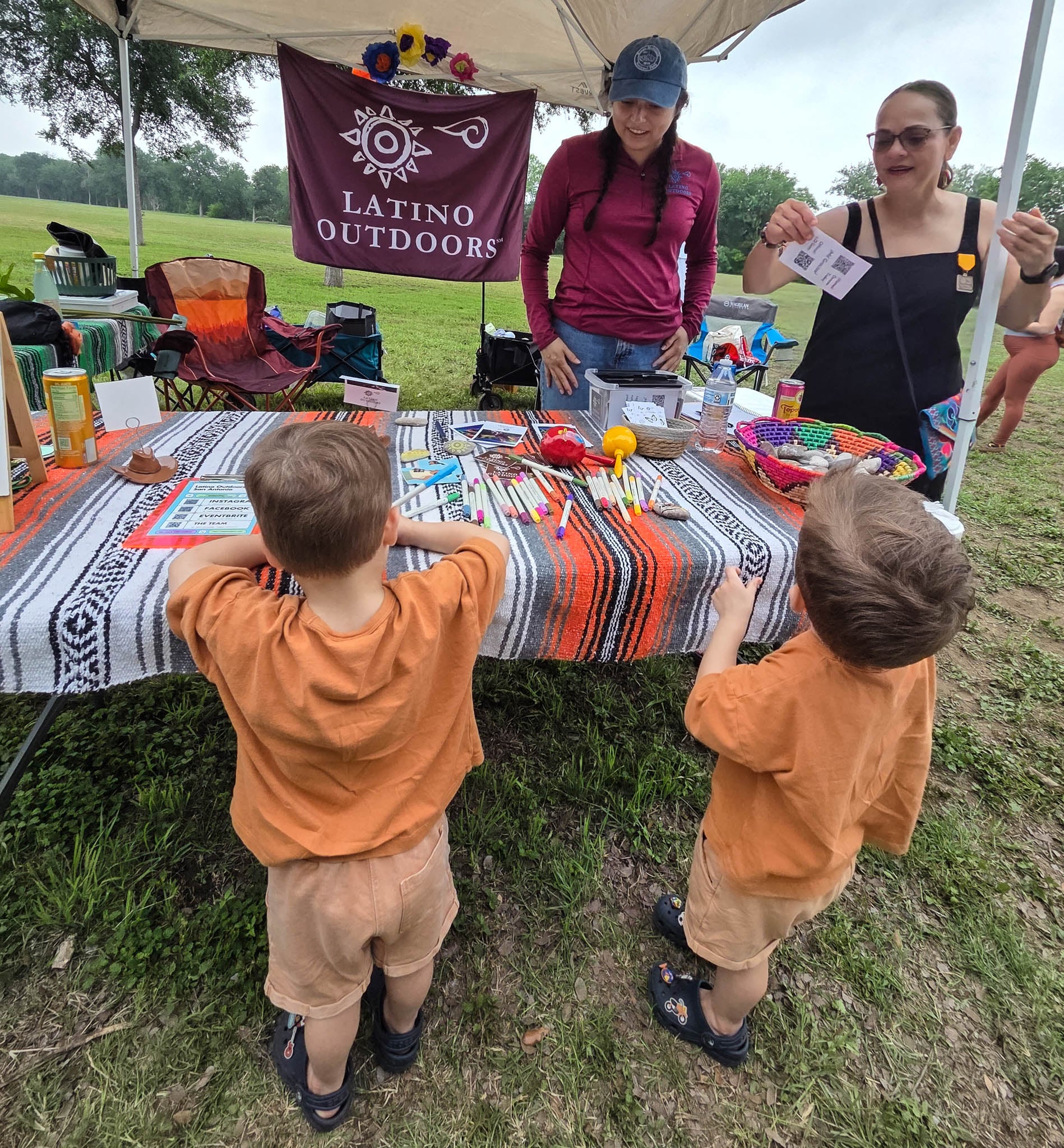 Two kids interact with a Latino Outdoors activity tent.