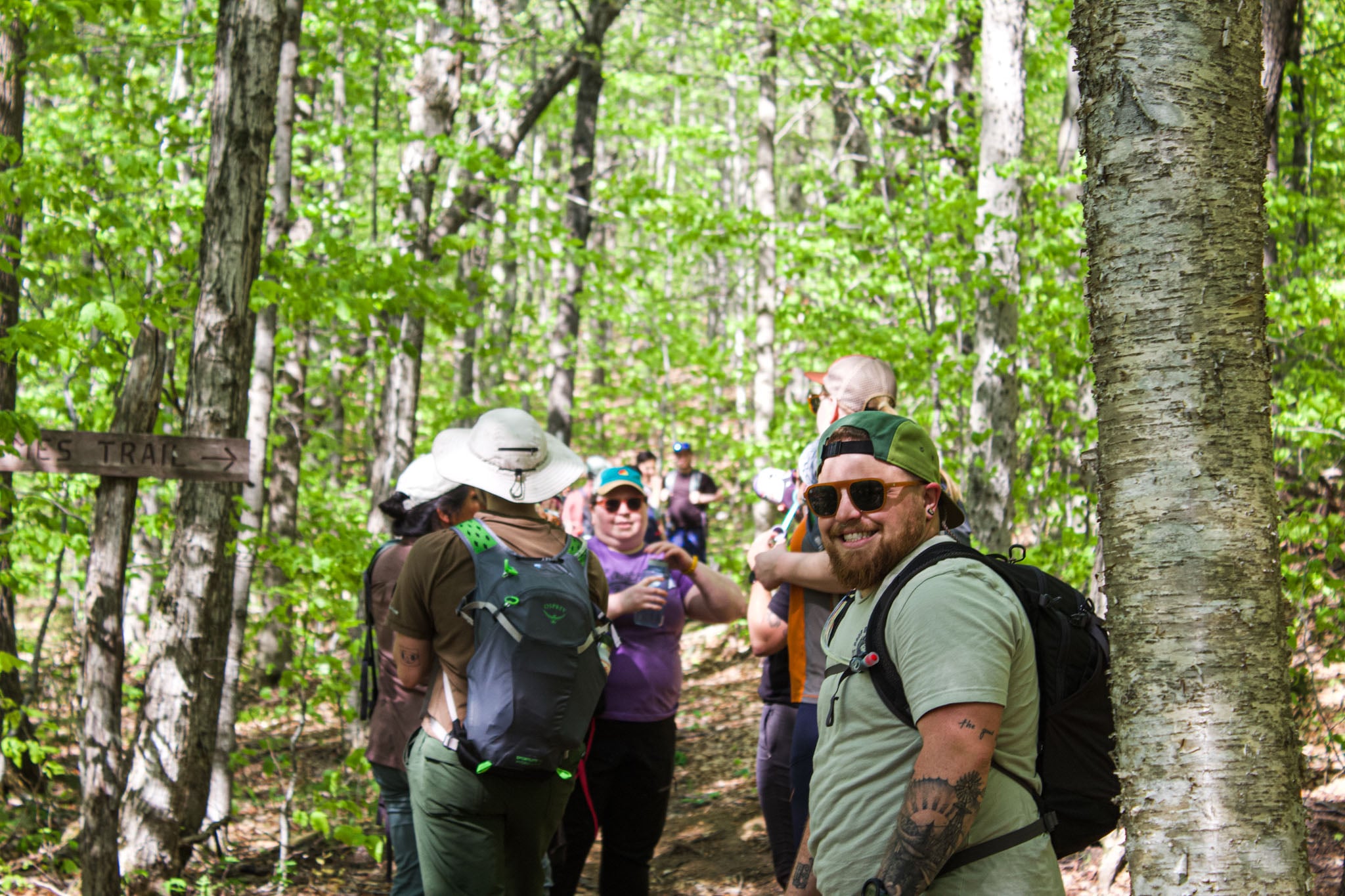A group of people rest on a trail in the woods.