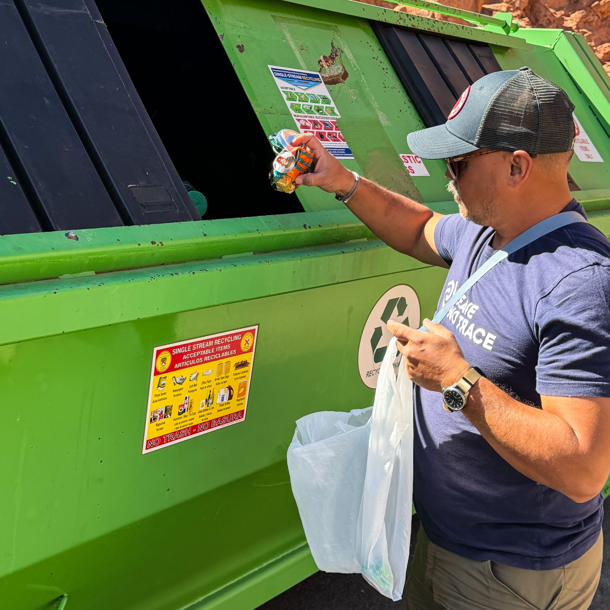 A person throws cans into a recycling bin.