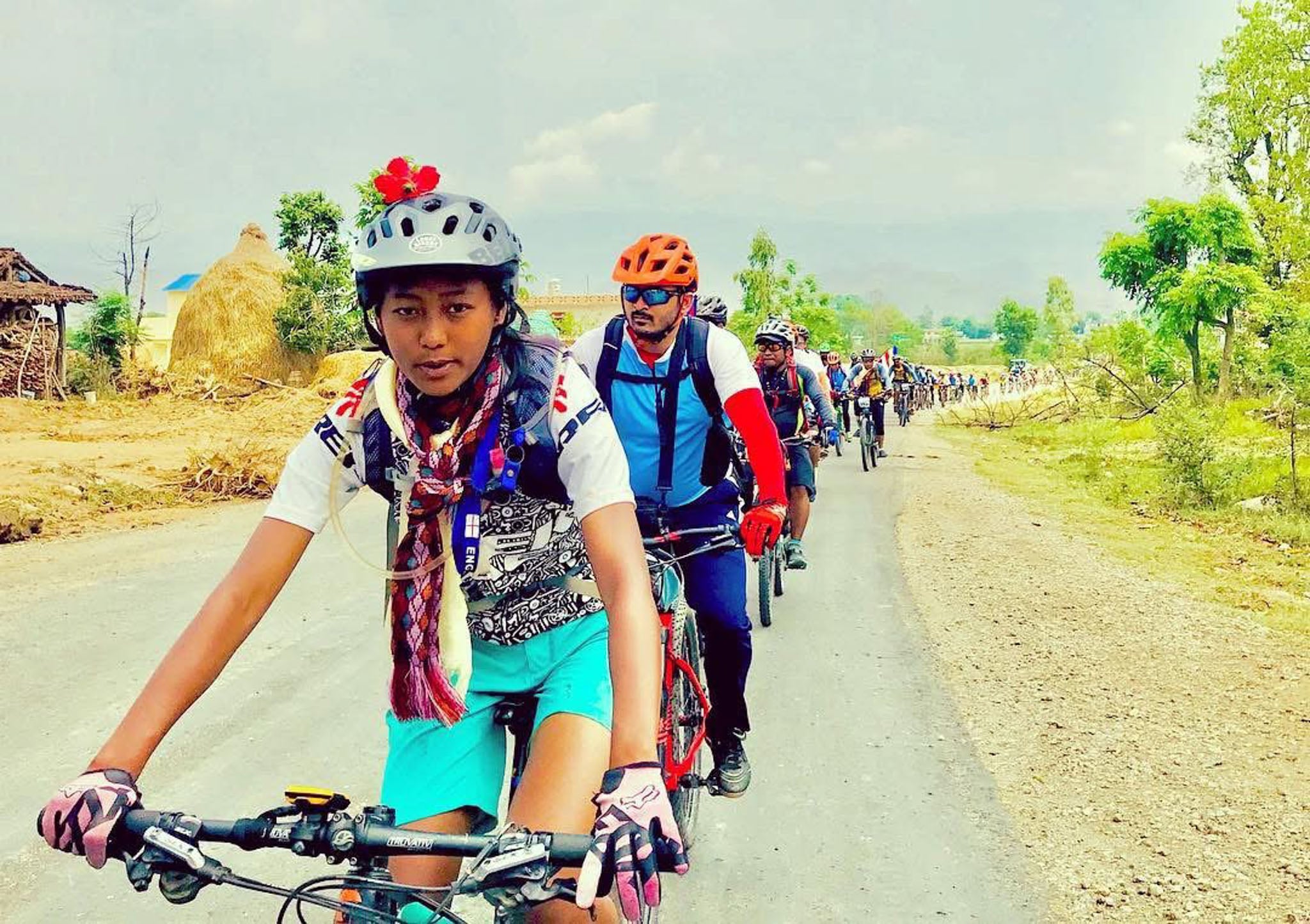 A woman leads a group of cyclists down a road.