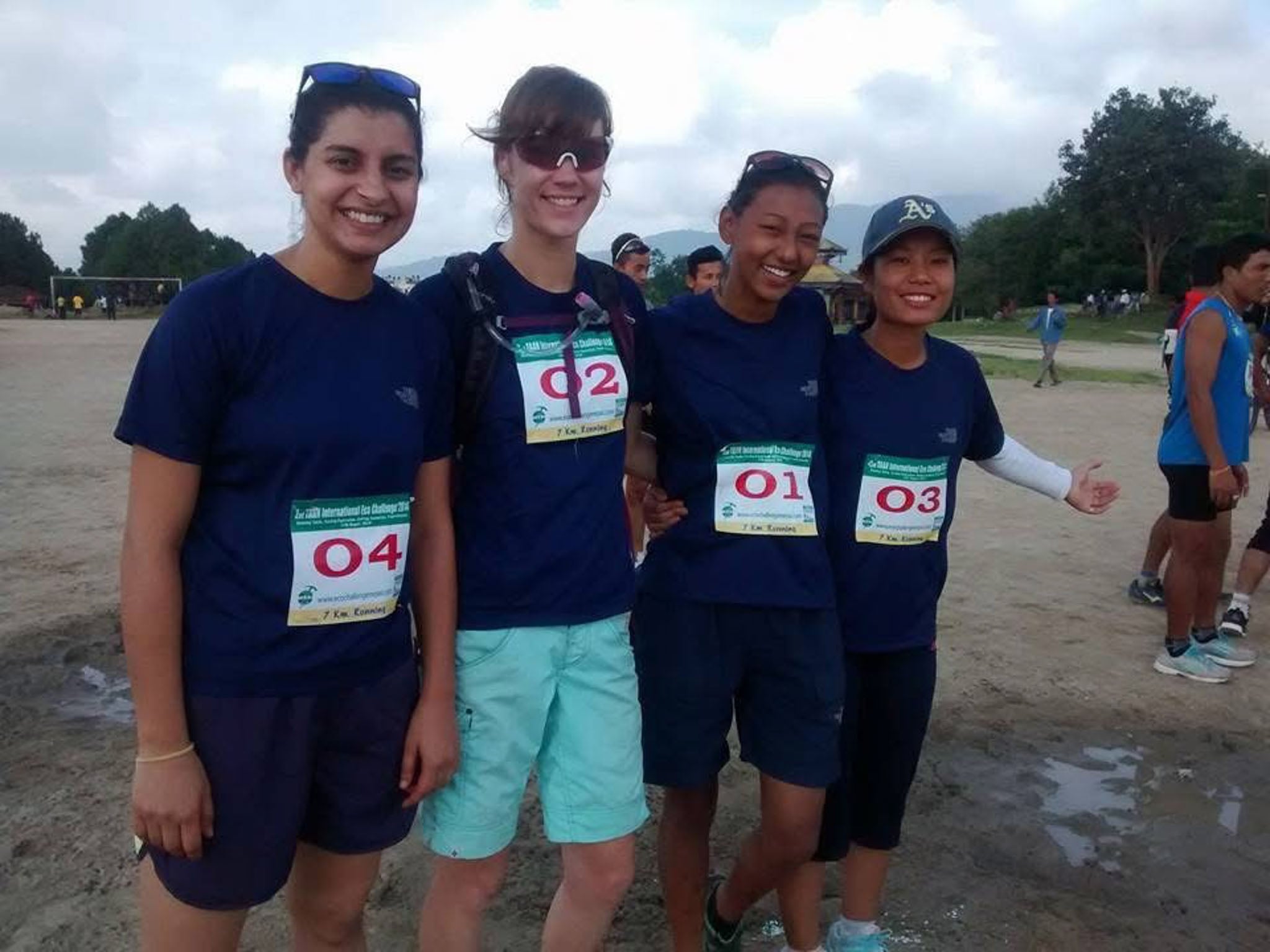 Four people pose for the camera with their race bibs on.