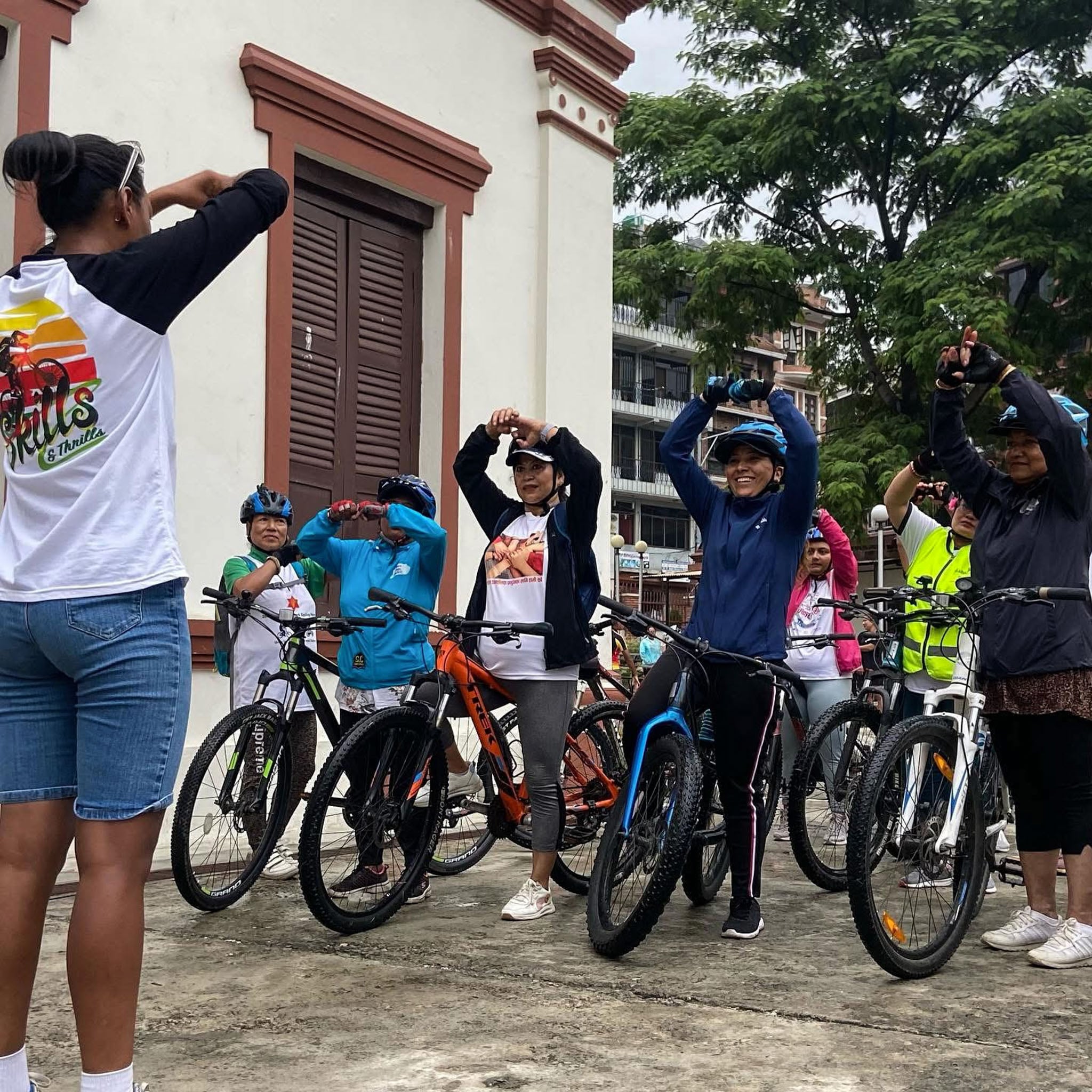 A group of riders hold their hands above their heads, mirroring their instructor.