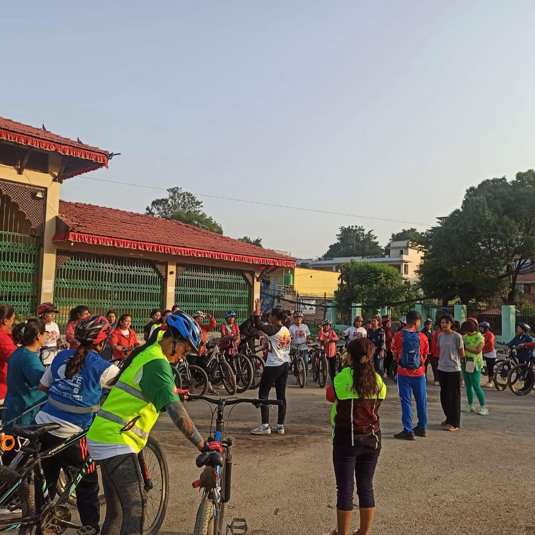 A large group of cyclists gather around an instructor.