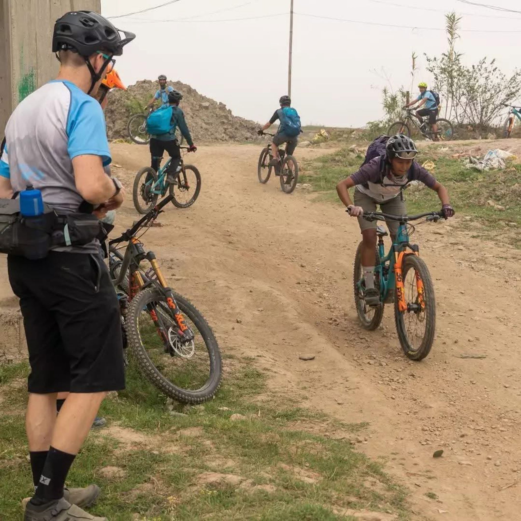 An instructor looks on as people cycle past.
