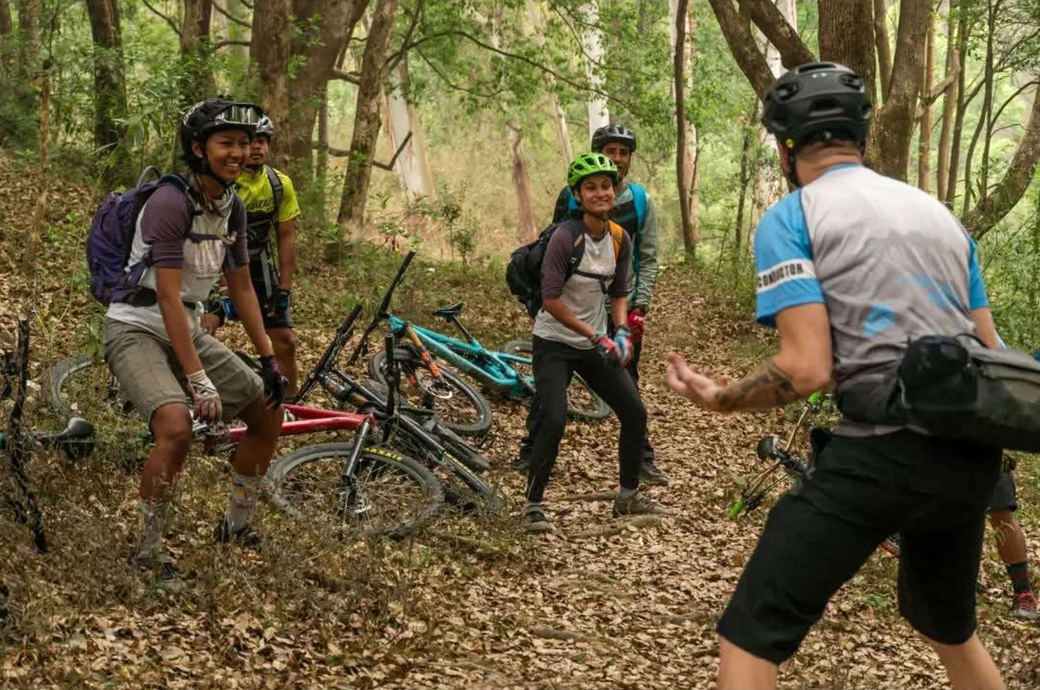 An instructor teaches a group of cyclists on the trail.
