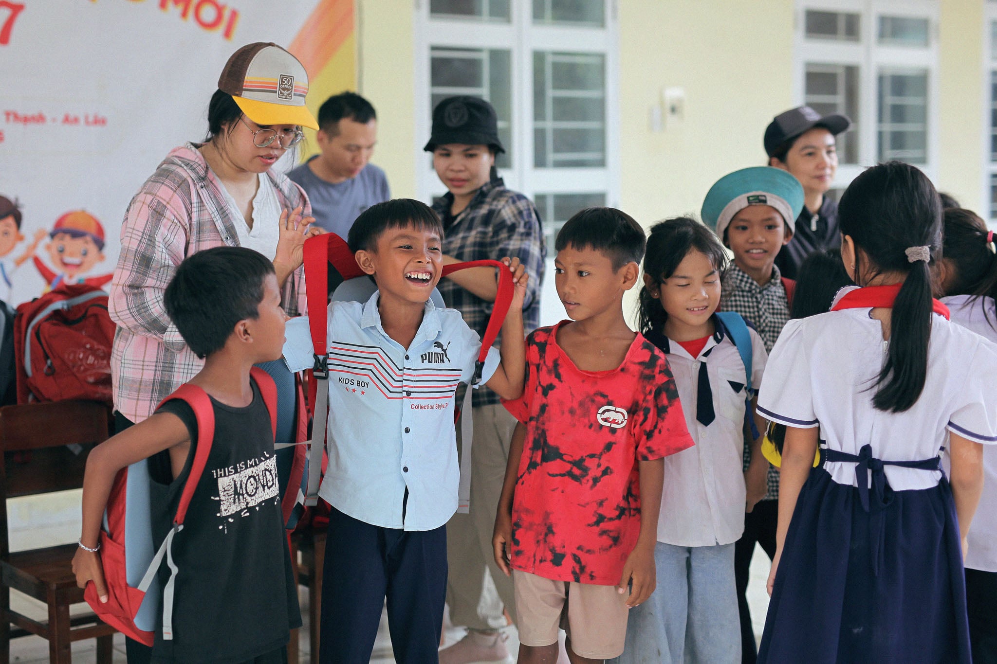 A group of kids get fitted with backpacks.