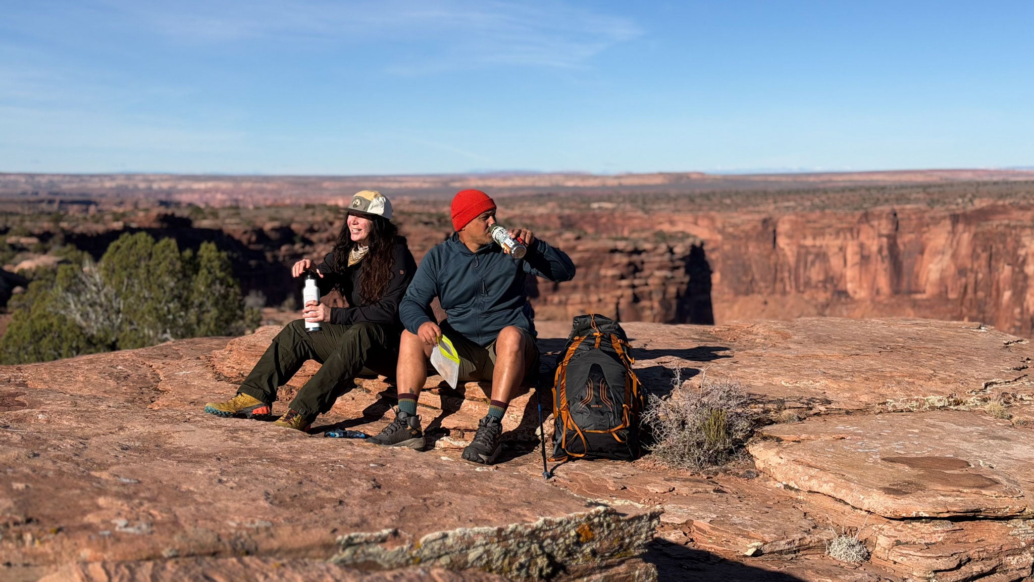 Two people rest for a snack break on a rocky trail.
