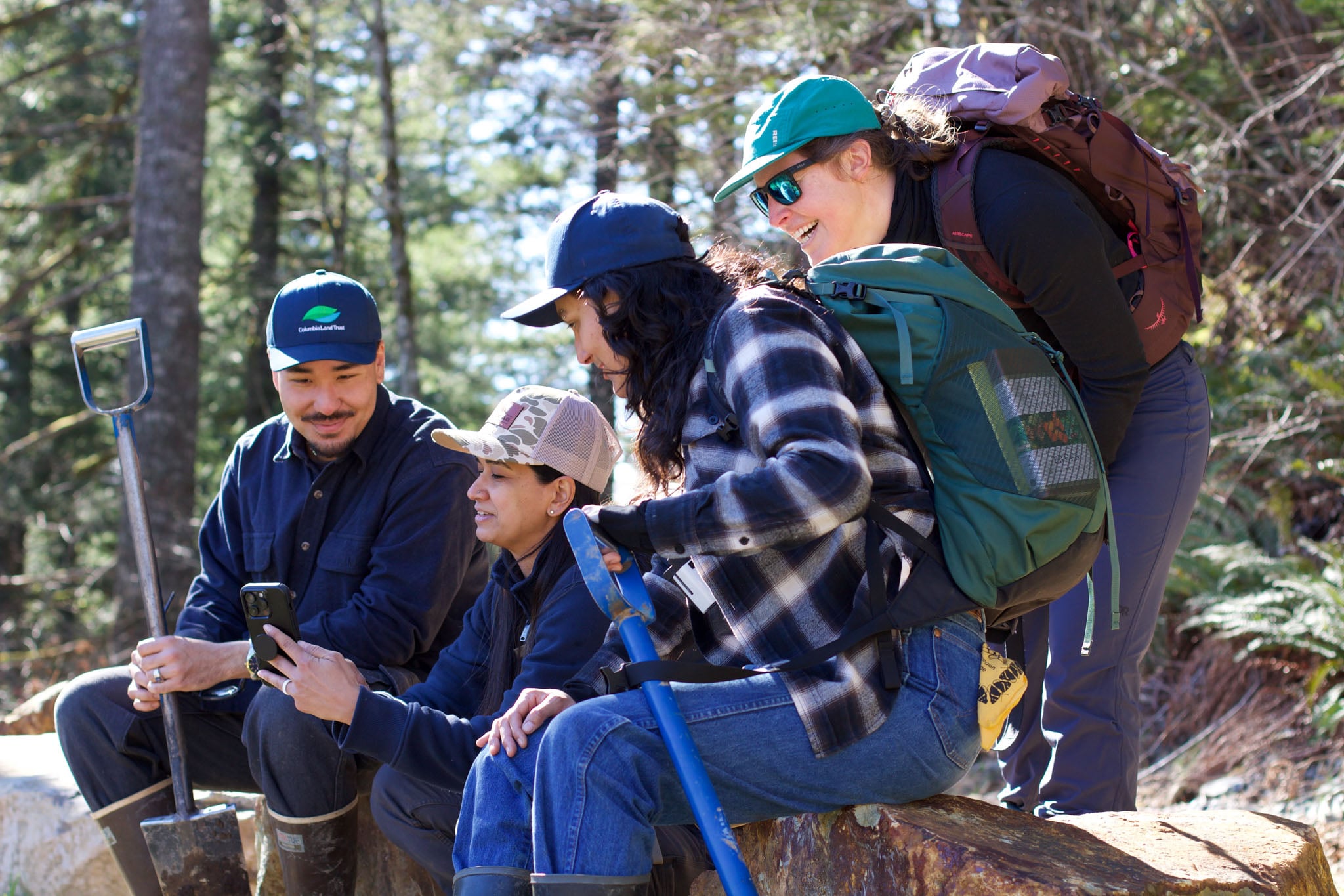 A group of people gather around with their tools and look at a phone screen.