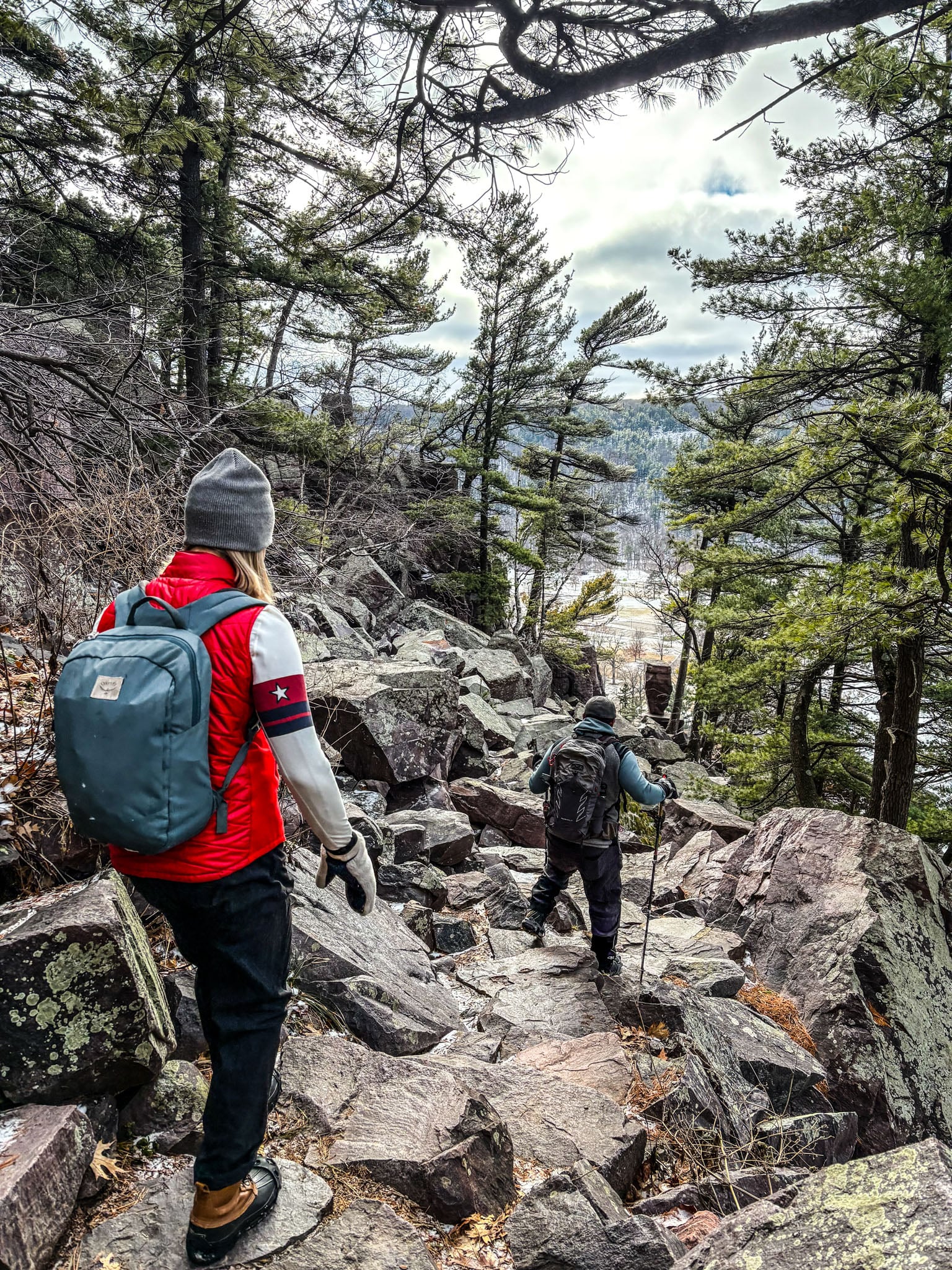 Two people walk away from the camera down a rocky hill.