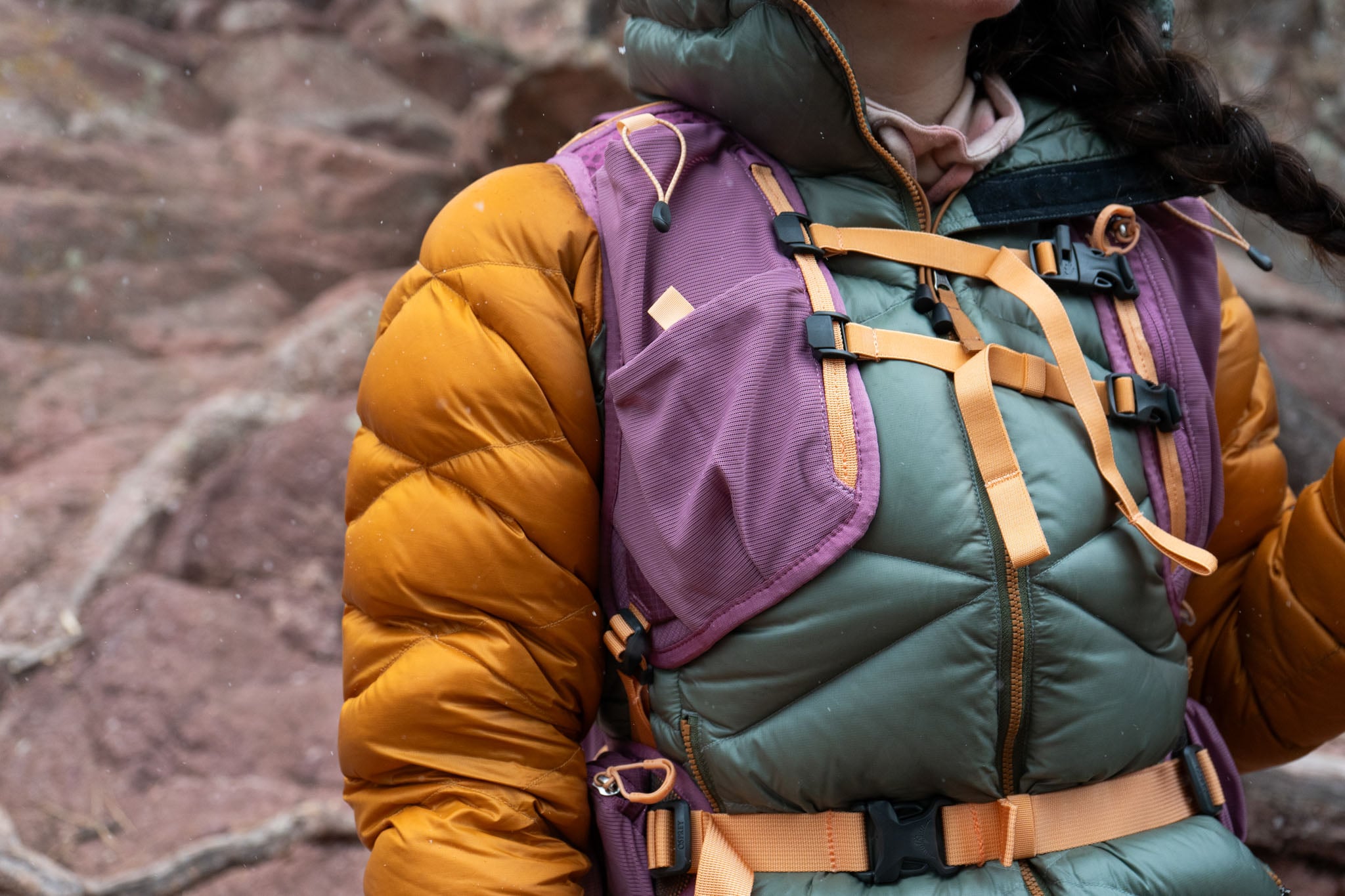 Close up of the front sternum straps of a hiking vest on a person.