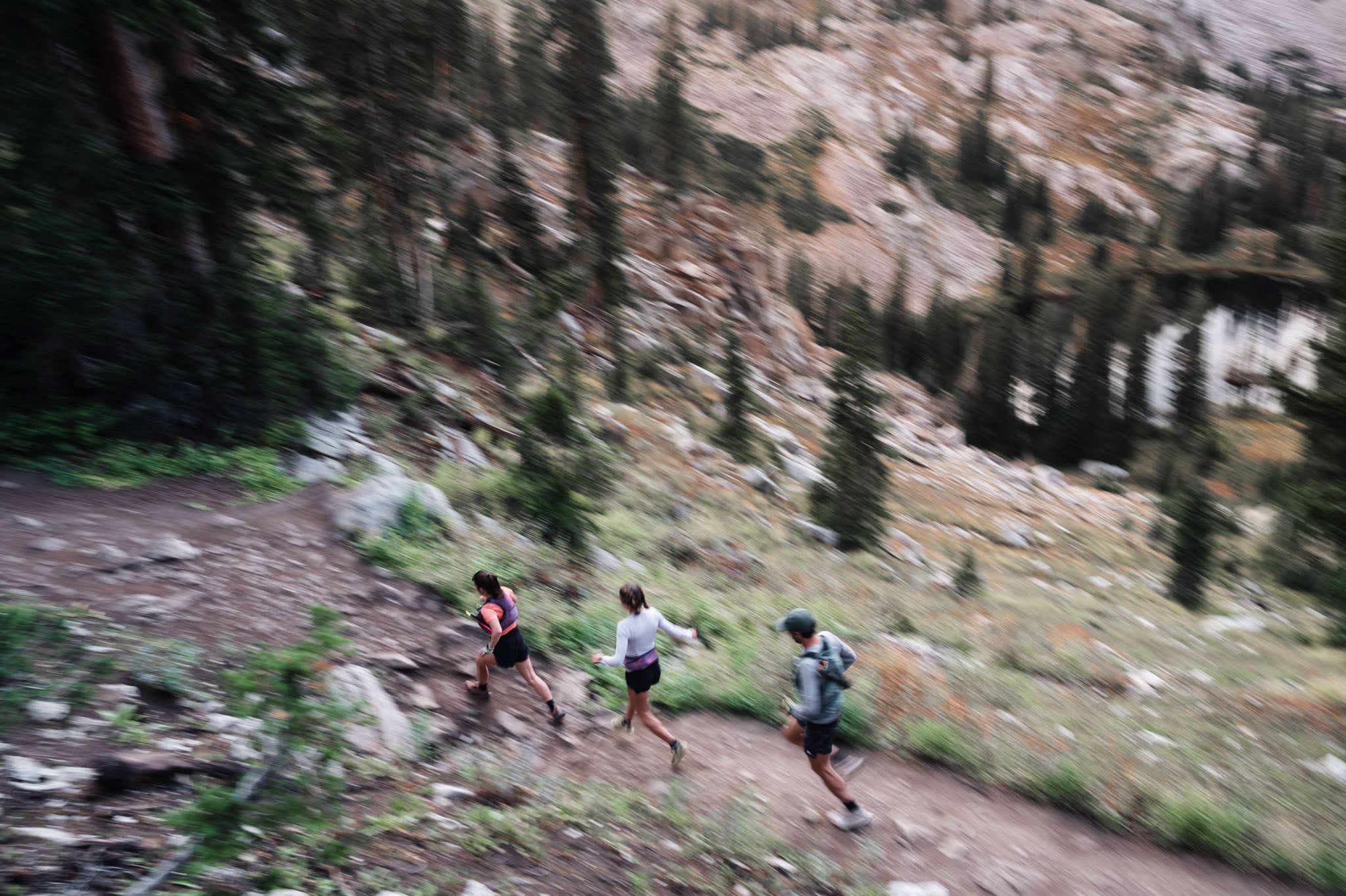 Three people run on a trail, blurry and shot from above.