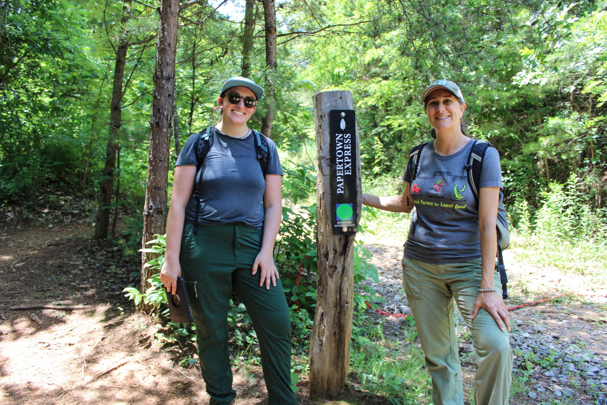 Two people pose next to a trail sign.