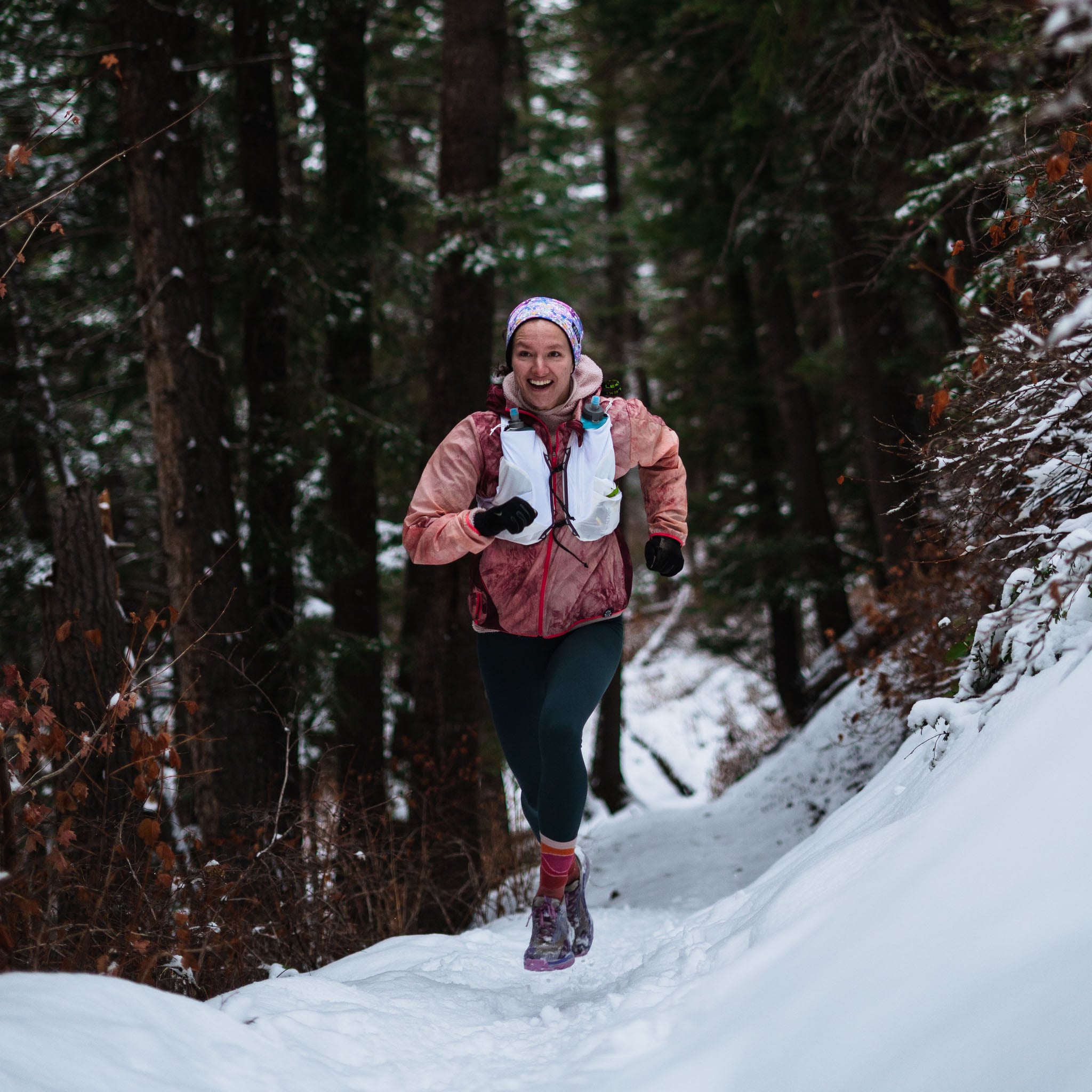 A person runs along a snowy forest trail.