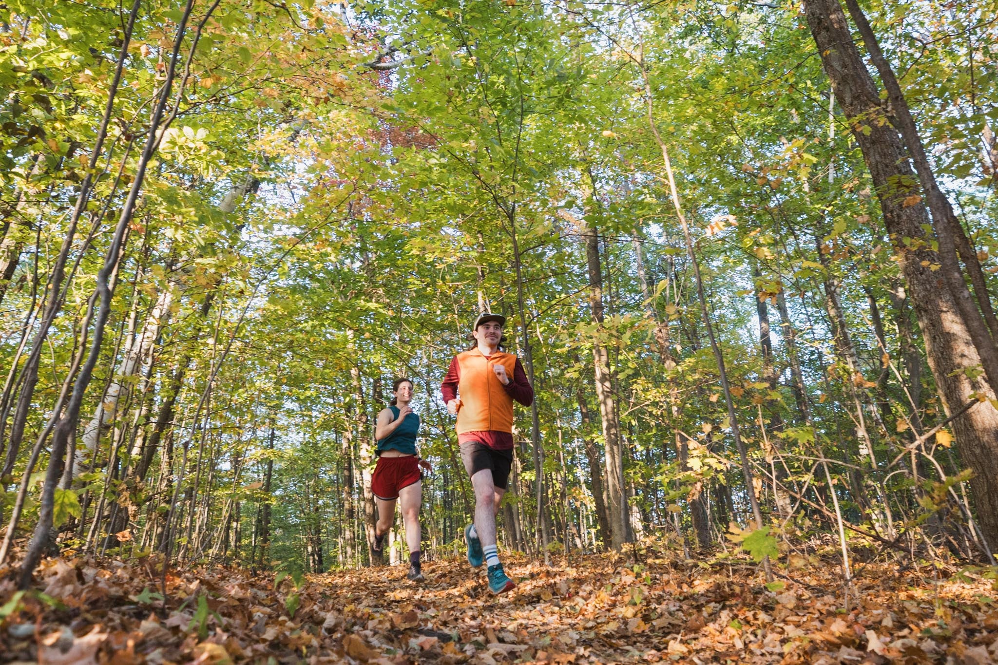 Two people run down a path in the forest.